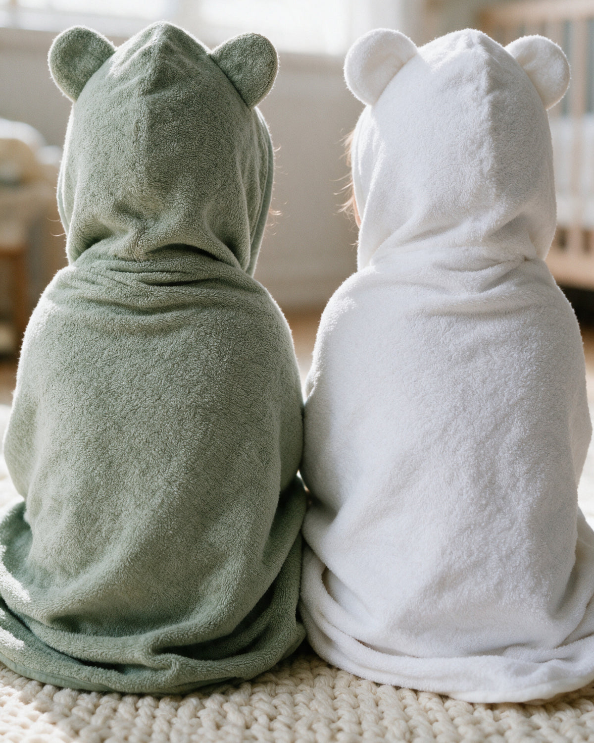 Two toddlers seen from behind in the Raccoon and Little Bear hooded towels, ears up