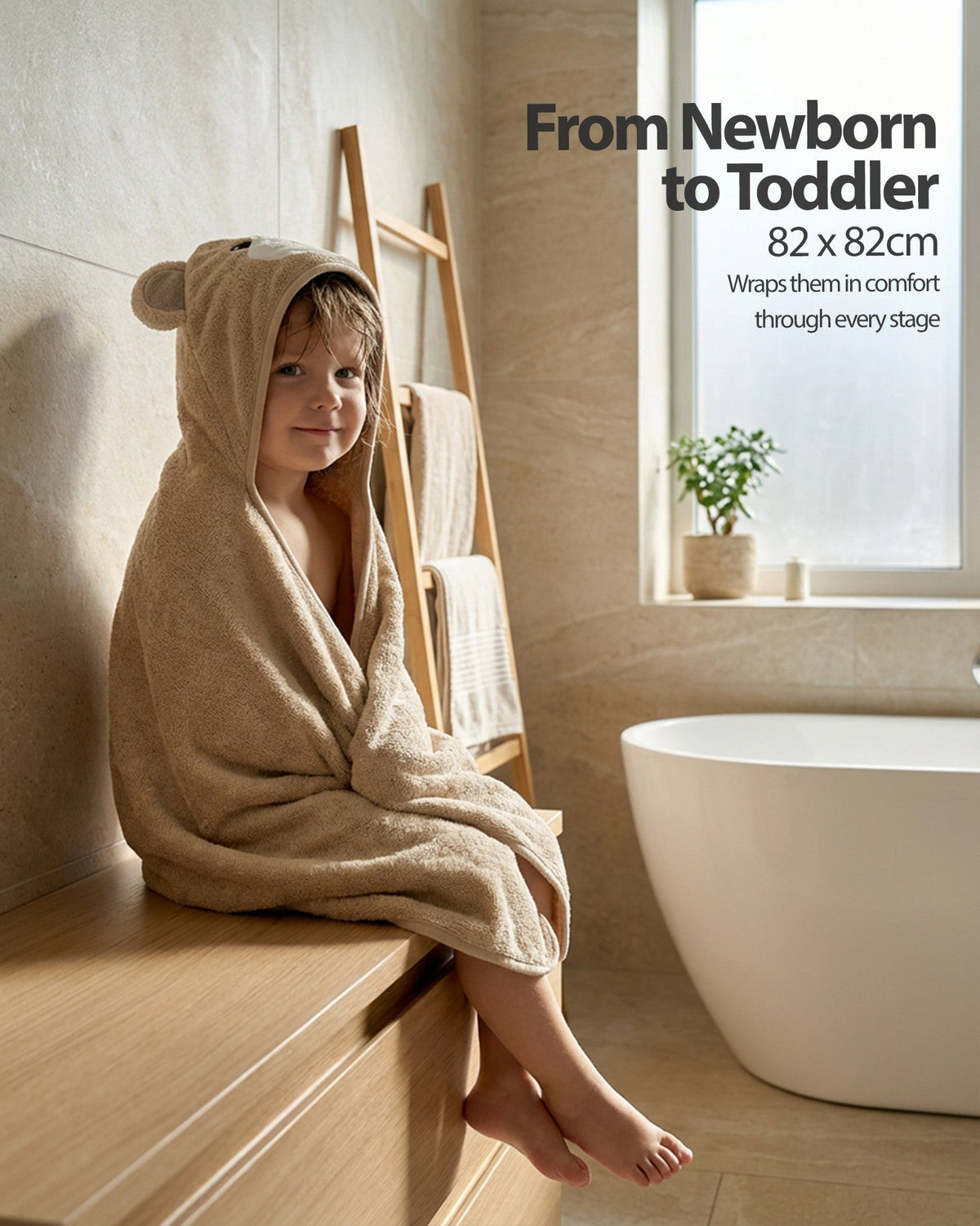 From newborn to toddler – a child sitting wrapped in the Cream Bear towel
