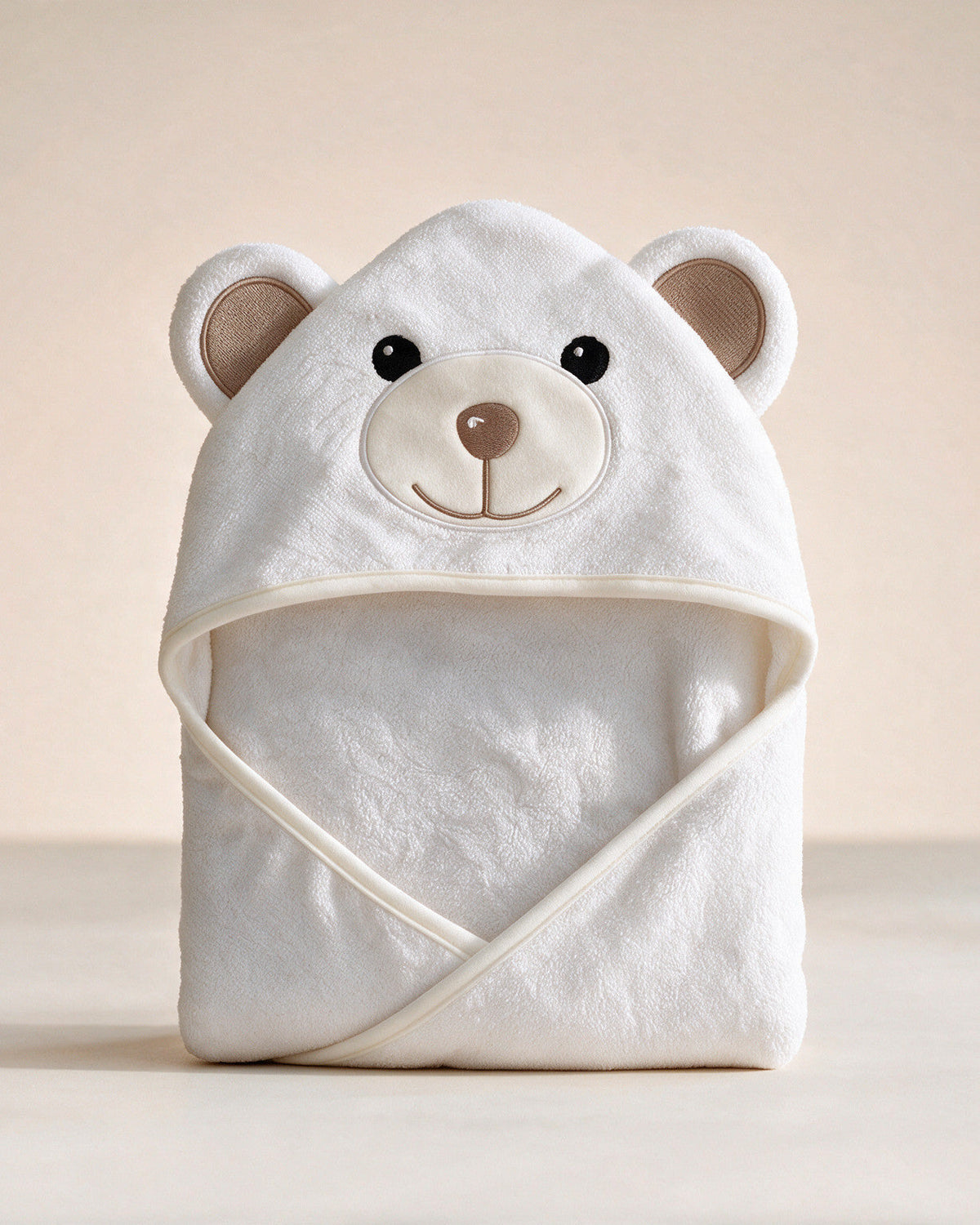 Little Bear hooded baby towel in white with taupe ears, on a cream background