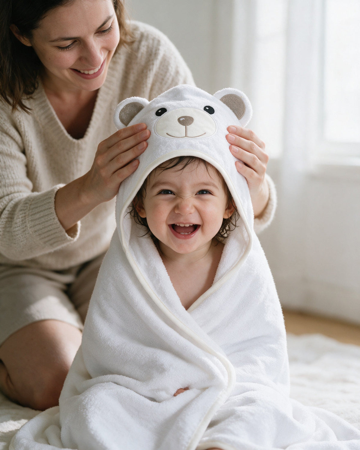 Mother adjusting the bear hood on her laughing toddler