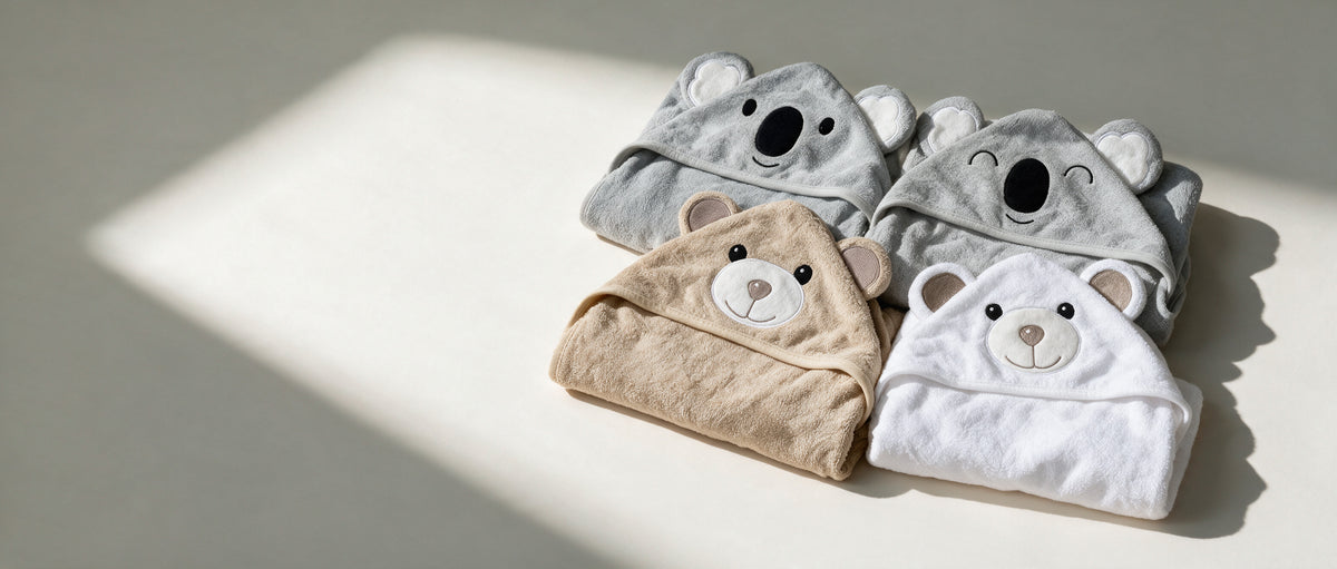 Four MiniBoo hooded towels, the Koala, Sleepy Koala, Cream Bear and White Bear, folded in soft window light