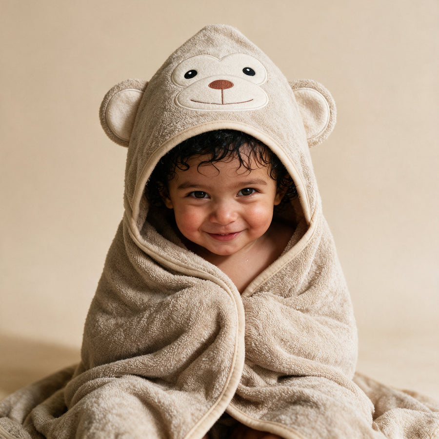 Toddler smiling in The Monkey hooded towel