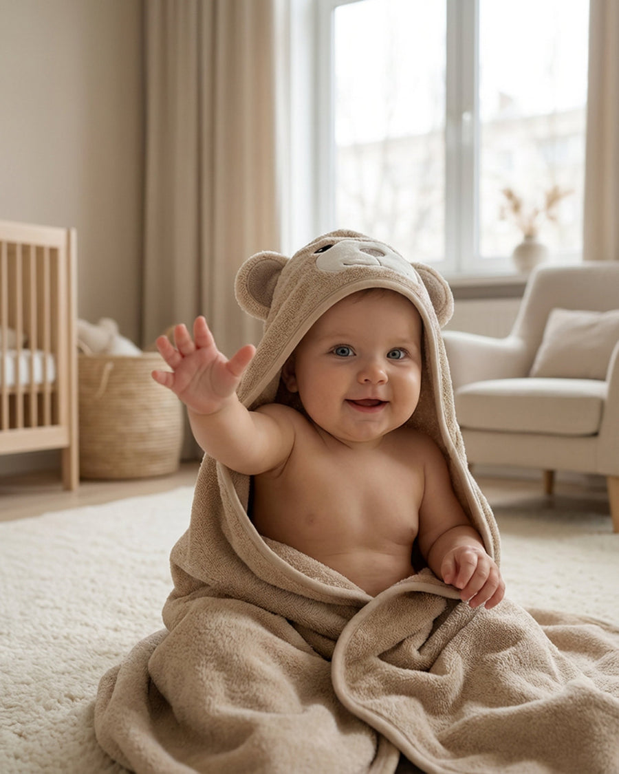 Baby waving, wrapped in the Cream Bear hooded towel
