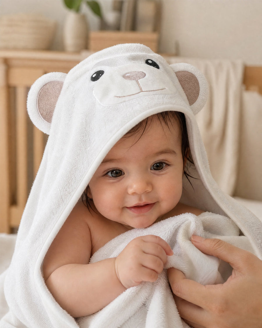 Smiling baby wrapped in The Bear hooded towel