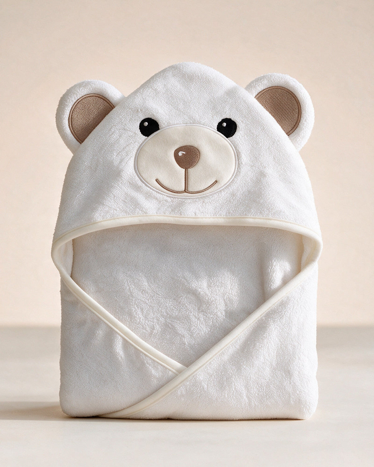 The Bear hooded baby towel, 90 × 90 cm, in white bamboo terry on a cream background