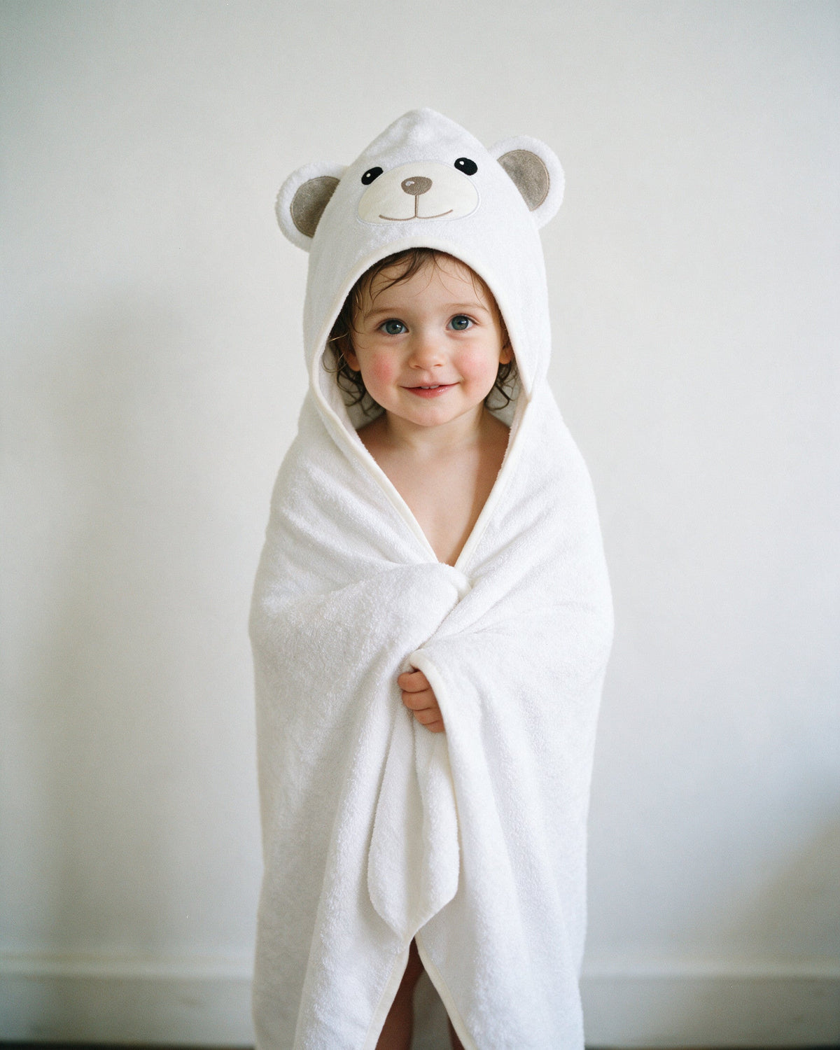 Toddler standing wrapped head to toe in The Bear hooded towel