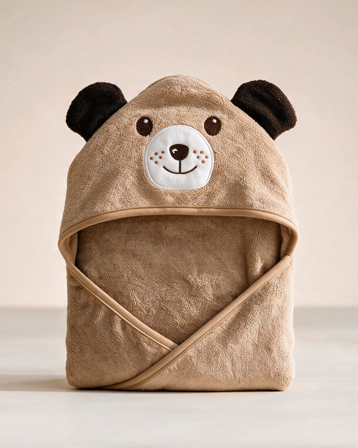 The Dog hooded baby towel in caramel brown, standing on a cream background