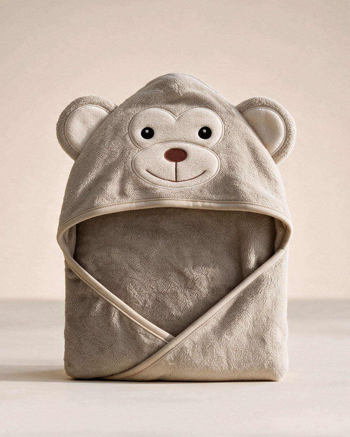 Kapuzenhandtuch The Monkey für Babys in Cremebeige, vor cremefarbenem Hintergrund