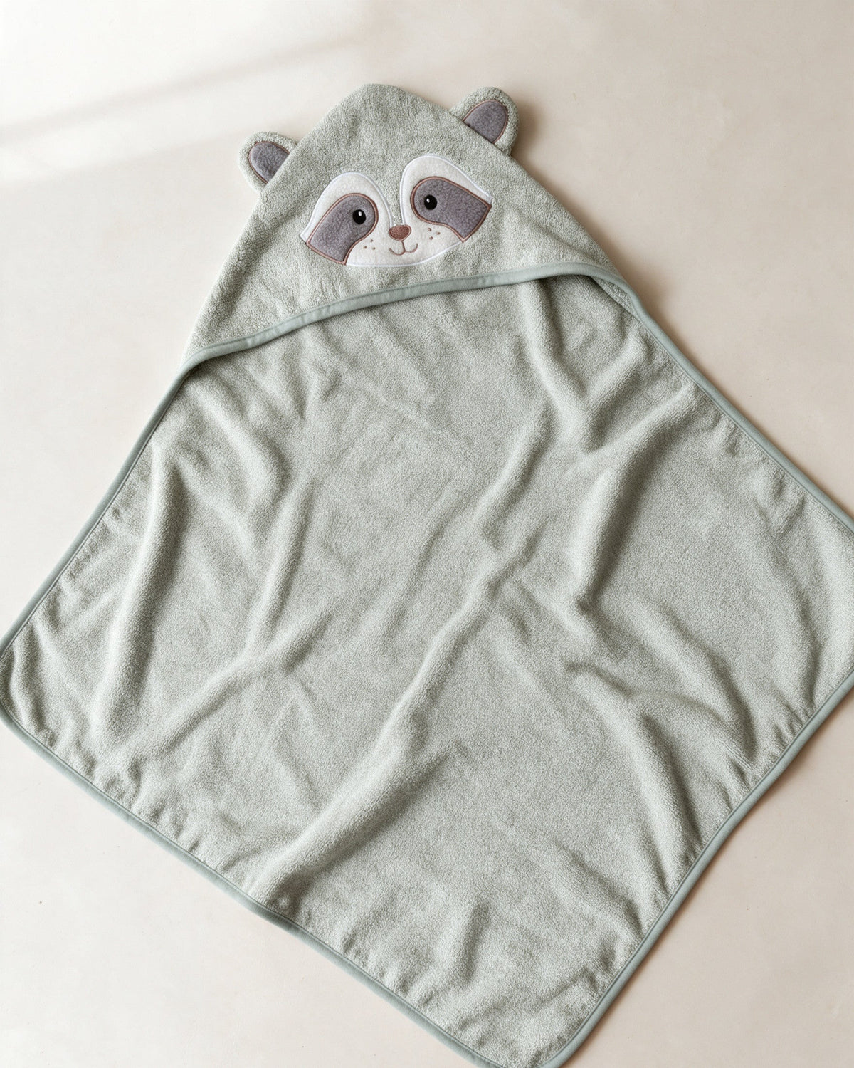 The Raccoon towel laid flat – a square towel with a corner hood
