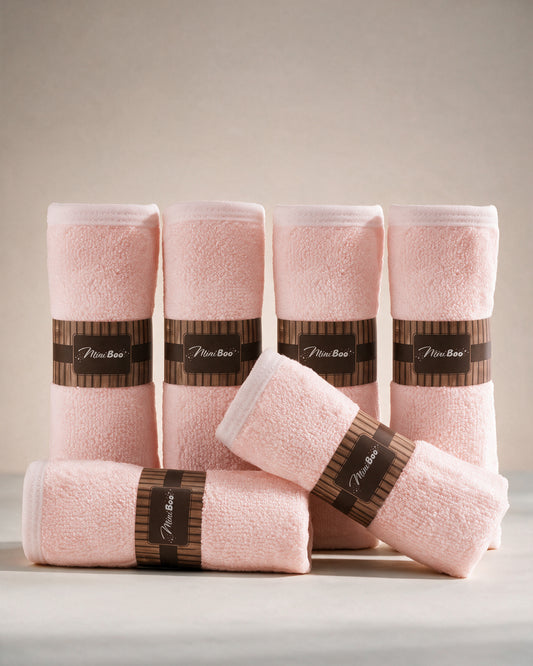 MiniBoo pink baby washcloths, a set of six rolled with brown paper bands, on a warm cream background