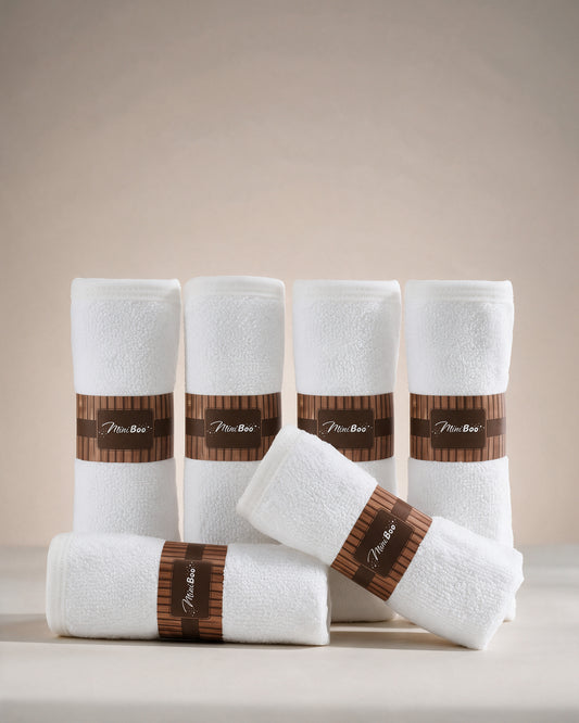 MiniBoo white baby washcloths, a set of six rolled with brown paper bands, on a warm cream background